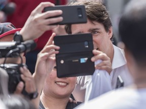 People pose for selfies with Prime Minister Justin Trudeau during a visit to the EVRAZ Regina steel factory in Regina on Sunday.