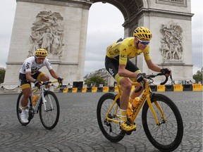 FILE - In this  July 23, 2017 file photo Britain's Chris Froome, wearing the overall leader's yellow jersey, is followed by teammate Colombia's Sergio Henao Montoya, as they pass the Arc de Triomphe during the twenty-first and last stage of the Tour de France cycling race in Paris. Chris Froome has been cleared of doping by the International Cycling Union in a decision that should allow him to pursue a record-tying fifth Tour de France title.