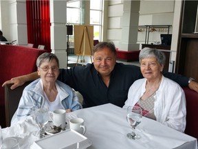 The two surviving Dionne quintuplets will be returning this week to the log cabin where they were born for a ceremony marking their birth as an event of national historic significance. Cecile Dionne, left, and sister Annette pose for a photo with Carlo Tarini in a June, 2018, handout image.