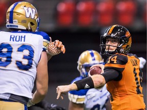 B.C. Lions quarterback Travis Lulay (14) passes as Winnipeg Blue Bombers' Craig Roh is held back by the offensive line during the second half of a CFL football game in Vancouver, on Saturday July 14, 2018.