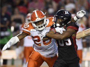 Redblacks kick returner Diontae Spencer wraps up the football as the Lions' Bo Lokombo (20) tries to strip it from his grasp on a first-half play.