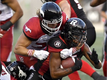 Ottawa Redblacks Loucheiz Purifoy (5) is tackled by Calgary Stampeders Ante Milanovic-Litre (34) during first half CFL action in Ottawa on Thursday, July 12, 2018.