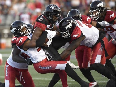 Ottawa Redblacks William Powell (29) gets tackled by Calgary Stampeders Jameer Thurman (56) during first half CFL action in Ottawa on Thursday, July 12, 2018.
