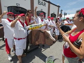 In this photo provided by the Florida Keys News Bureau, Ernest Hemingway look-alikes have their picture taken with visitors amid fake bulls outside Sloppy Joe's Bar Saturday, July 21, 2018, in Key West, Fla. The island city's annual Hemingway Days festival continues through Sunday, July 22. Hemingway lived and wrote in Key West throughout most of the 1930s.