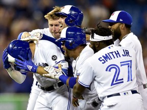 Toronto Blue Jays shortstop Aledmys Diaz (1) is mobbed by teammates after hitting the game-winning single scored by teammate Russell Martin, not shown, during tenth inning MLB baseball action against the Baltimore Orioles, in Toronto on Friday, July 20, 2018.
