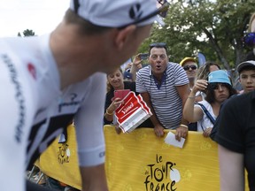 A man, center, expresses his disapproval of Britain's Chris Froome, left, by booing prior to the start of the fifteenth stage of the Tour de France cycling race over 181.5 kilometers (112.8 miles) with start in Millau and finish in Carcassonne, France, France, Sunday July 22, 2018. Froome was cleared of doping by the International Cycling Union in a decision that will allow him to pursue a record-tying fifth Tour de France
