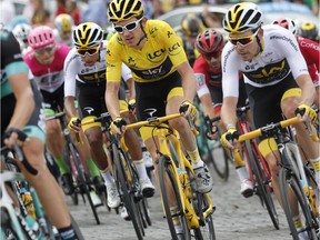 Tour de France winner Britain's Geraint Thomas, wearing the overall leader's yellow jersey, and teammates Colombia's Egan Arley Bernal Gomez, to his left, and Britain's Luke Rowe, to his right, ride during the twenty-first stage of the Tour de France cycling race over 116 kilometers (72.1 miles) with start in Houilles and finish on Champs-Elysees avenue in Paris, France, Sunday July 29, 2018.