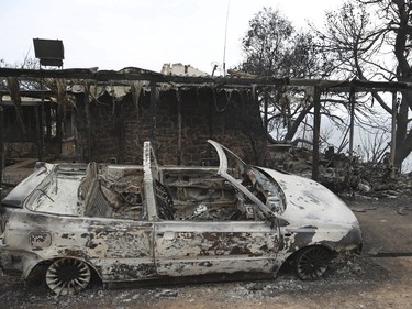 A man reacts next to a burned-out car in Mati east of Athens, Tuesday, July 24, 2018. Twin wildfires raging through popular seaside areas near the Greek capital have torched homes, cars and forests and killed at least 49 people, authorities said Tuesday, raising the death toll after rescue crews reported finding the bodies of more than 20 people huddled together near a beach.