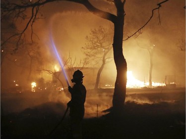 A firefighter sprays water on the fire in the town of Mati, east of Athens, Monday, July 23, 2018. Regional authorities have declared a state of emergency in the eastern and western parts of the greater Athens area as fires fanned by gale-force winds raged through pine forests and seaside settlements on either side of the Greek capital.