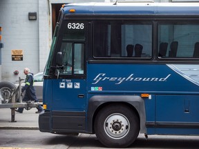 A worker walks past a Greyhound bus sitting idle, in Vancouver, on Monday July 9, 2018. Greyhound Canada says it is ending its passenger bus and freight services in Alberta, Saskatchewan and Manitoba, and cancelling all but one route in B.C. -- a U.S.-run service between Vancouver and Seattle. As a result, when the changes take effect at the end of October, Ontario and Quebec will be the only regions where the familiar running-dog logo continues to grace Canadian highways.