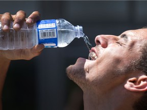 Abdallah Karoubi enjoys a cool drink after working to remove tents at Lansdowne Park as the region continued to experience a heat wave.   Photo by Wayne Cuddington/ Postmedia