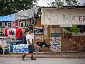 Members of 'Camp Cloud' walk along the road next to their camp near the entrance of Kinder Morgan's Trans Mountain pipeline facility in Burnaby, British Columbia on July 19, 2018.