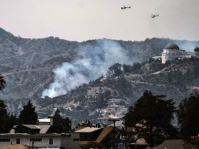 Water dropping helicopters fly over the Griffith Observatory in Los Angeles as a wildfire burns along the hillsides sending up huge plumes of smoke visible throughout the city Tuesday, July 10, 2018. Los Angeles Fire Department officials say the fire damaged some cars parked in area but nobody was hurt.