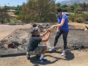 In this photo provided by the Santa Barbara County Fire Department resident Ishu Rao on one knee, places this wife's wedding ring on her finger, next to the charred remains of their home in Goleta, Calif., Sunday, July 8, 2018. The California couple who lost their home in a wildfire made a new happy memory amid the ashes when they found what was left of Laura Rao's wedding ring. Ishu and Laura Rao returned to the rubble of their home of three years on Sunday, to look for her Tiffany ring. They searched with the help of some firefighters in the area and Ishu Rao made the find, prompting him to get down on one knee and again propose to his bride.