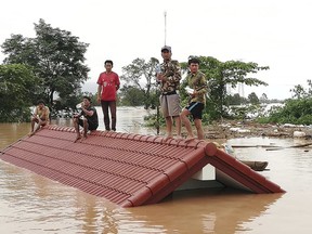 Villagers take refuge on a rooftop above flood waters from a collapsed dam in the Attapeu district of southeastern Laos, Tuesday, July 24, 2018.