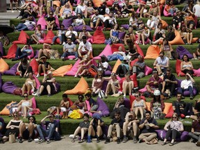 People watch "The Never Ending Story" movie on an outdoor cinema screen at Canalside Steps, Granary Square, London, Thursday, June 28, 2018, during hot weather.