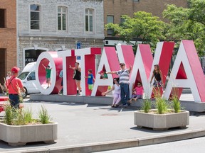 Tourists pose with the Ottawa sign as a study is planned for the Byward Market on use of public spaces. It comes as the city also scrutinizes Sparks St.   Photo by Wayne Cuddington/ Postmedia