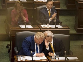 Premier Doug Ford leans in to listen to Finance Minister Victor Fedeli during the first Session of the 42nd Parliament of Ontario at Queen's Park in Toronto on Thursday.