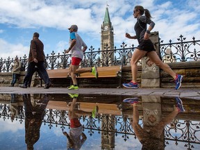 Runners jog past puddles on Wellington St as clouds and rain finally gave way to sunny skies on Parliament Hill.
