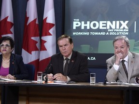 Sen. Percy Mockler, centre, chair of the Standing Senate Committee on National Finance, sits with deputy chairs Sen. Mobina Jaffer, left, and Sen. Andre Pratte, of the Standing Senate Committee on National Finance, listen to questions during a press conference on their report on the Phoenix pay system, in Ottawa on Tuesday, July 31, 2018.