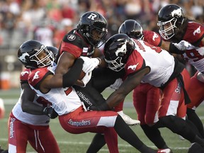 Ottawa Redblacks William Powell (29) gets tackled by Calgary Stampeders Jameer Thurman (56) during first half CFL action in Ottawa on Thursday, July 12, 2018. (THE CANADIAN PRESS/Justin Tang)