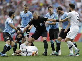 Uruguay players protest to referee Nestor Pitana of Argentina that France's Kylian Mbappe, on the ground, is overreacting after taking a dive during the quarterfinal match between Uruguay and France at the 2018 soccer World Cup in the Nizhny Novgorod Stadium, in Nizhny Novgorod, Russia, Friday, July 6, 2018.