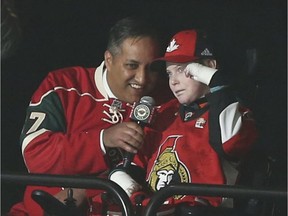 Wearing a Senators jersey, Jonathan Pitre, right, helps Canadian Consul General Khawar Nasim with the "Let's Play Hockey" call before a game against the Minnesota Wild in St. Paul, Minn., on March 30, 2017.