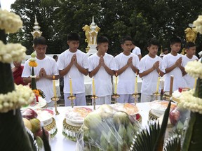 Soccer coach Ekkapol Janthawong, left, and members of the rescued soccer team attend a Buddhist ceremony believed to extend the lives of its attendees as well as ridding them of dangers and misfortunes in the Mae Sai district, Chiang Rai province, northern Thailand, Tuesday, July 24, 2018. Eleven of the boys and their coach rescued last week from the flooded Tham Luang cave are attending a merit-making ceremony at a Buddhist temple. The boys are also expected to have their heads shaved in the afternoon in preparation for their ordination as Buddhist novices.