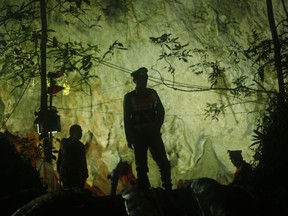 In this Monday, July 2, 2018, file photo, Thai police stand in front of the entrance to a cave complex where 12 boys and their soccer coach went missing in Mae Sai, Chiang Rai province, in northern Thailand.