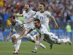 Russia's Fyodor Smolov, right, dives as he celebrates with teammates after Russia defeated Spain in a penalty shoot out during the round of 16 match between Spain and Russia at the 2018 soccer World Cup at the Luzhniki Stadium in Moscow, Russia.