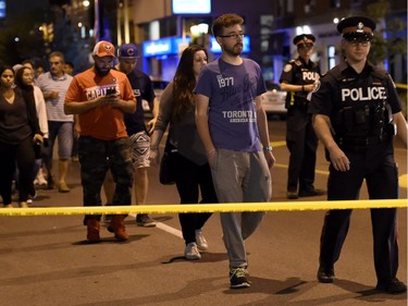 Civilians are escorted from the scene of a mass casualty incident in Toronto on Sunday, July 22, 2018.