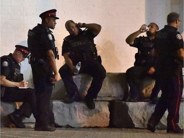 Police officers rest at the scene of a mass casualty incident in Toronto on Monday, July 23, 2018.
