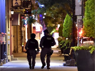 Tactical police officers walk along Danforth Avenue at the scene of a mass casualty incident in Toronto on Monday, July 23, 2018.