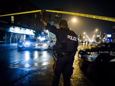 A police officer lifts police tape near the scene of a shooting in east Toronto, on Monday, July 23, 2018.