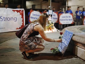 A woman places a flower at a vigil remembering the victims of a shooting on Sunday evening on Danforth, Ave. in Toronto on Monday, July 23, 2018.