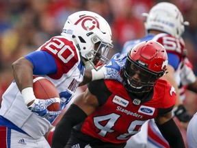 Montreal Alouettes' Tyrell Sutton, left, tries to get past Calgary Stampeders' Wynton McManis during first quarter CFL football action in Calgary, Saturday, July 21, 2018. THE CANADIAN PRESS/Jeff McIntosh