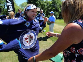 Brooke Henderson, LPGA golfer from Smiths Falls, Ont., finds her way into a Patrik Laine jersey gifted to her following a clinic at St. Charles Country Club in Winnipeg on Tues., July 17, 2018 .