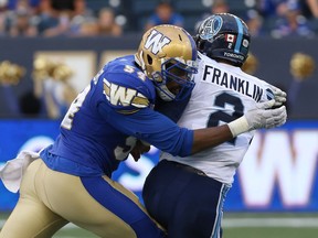 Winnipeg Blue Bombers DE Tristan Okpalaugo (left) hits Toronto Argonauts QB James Franklin during CFL action in Winnipeg on Fri., July 27, 2018.