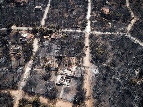 This Wednesday, July 25, 2018 aerial photo shows burnt houses and trees following a wildfire in Mati, east of Athens. Frantic relatives searching for loved ones missing in Greece's deadliest forest fire in decades headed to Athens' morgue on Thursday, July 26, 2018 as rescue crews and volunteers continued searches on land and at sea for potential further victims.