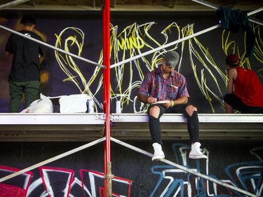 House of PainT festival took place Saturday August 25, 2018 under the Dunbar Bridge. An artist sits on the scaffolding working in a sketch book as other artists were starting their pieces under the bridge.
