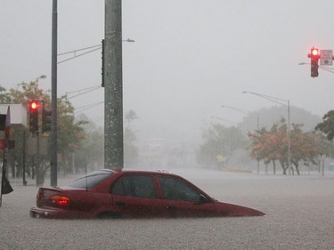 A car is stuck partially submerged in floodwaters from Hurricane Lane rainfall in Hilo on Thursday.