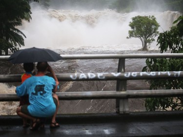 People watch the Wailuku River floods on the Big Island in Hilo, Hawaii, on Thursday.