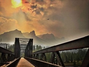 Smoke from the wildfires in B.C. blows into Canmore making an eerie scene as it colours the sky over the Engine Bridge on Wednesday, August 1, 2018.
