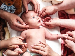 A baby surrounded by multiple people.