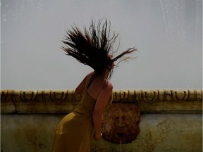 A woman refreshes herself in a fountain.