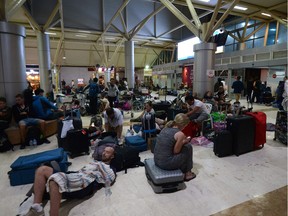 Tourists sleep on the floor as they wait to depart from Praya Lombok International Airport on the West Nusa Tenggara province on Sunday.