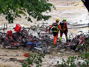 TOPSHOT - Rescuers walk past damaged bicycles in a flooded camping area as storms and heavy rains sweep across France on August 9, 2018 in Saint-Julien-de-Peyrolas, southern France.