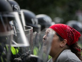 An activist confronts Virginia State Troopers in riot gear during a rally on the campus of The University of Virginia one-year after the violent white nationalist rally that left one person dead and dozens injured in Charlottesville, Virginia on August 11, 2018.