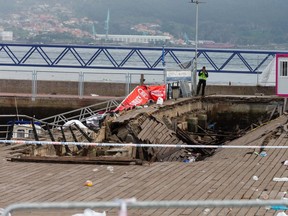 A police investigator inspects the seafront platform in Vigo on August 13, 2018 after a section of a wooden promenade suddenly collapsed with people watching a rap artist just before midnight on Sunday. - A total of 316 people were injured, including nine seriously, the regional government of Galicia said in a statement.