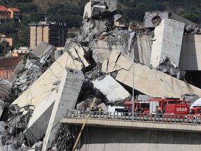 Rescuers work at the site where the Morandi motorway bridge collapsed in Genoa on August 14, 2018. - At least 30 people were killed on August 14 when the giant motorway bridge collapsed in Genoa in northwestern Italy. The collapse of the viaduct, which saw a vast stretch of the A10 freeway tumble on to railway lines in the northern port city, was the deadliest bridge failure in Italy for years, and the country's deputy transport minister warned the death toll could climb further.